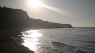 Kumsalda güneş doğarken koşan adam.