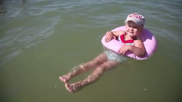 Uma menina flutua em um círculo de borracha — Vídeo de Stock