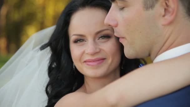 Braut und Bräutigam spazieren im Park und küssen sich — Stockvideo