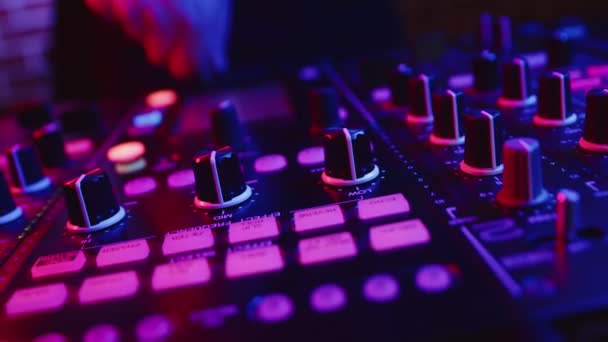 Closeup of professional DJ adjusting fader on digital music console in pink neon light in nightclub. Confident male hand controls digital DJ console. Concept neon party and modern club music — Stock Footage Closeup of professional DJ adjusting fader on digital music console in pink neon light in nightclub. Confident male hand controls digital DJ console. Concept neon party and modern club music — Stock Video
