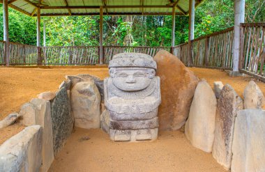 Kolombiya 'nın Huila eyaletinin San Agustin kentindeki UNESCO Dünya Mirası sahasında bulunan diğer taşlarla çevrili görkemli bir Kolombiya öncesi taş heykel..