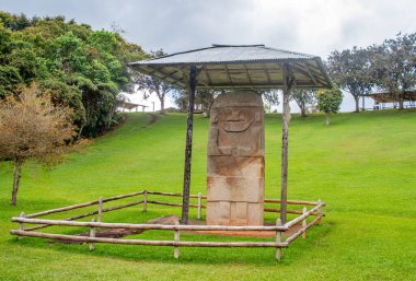 San Agustin Arkeoloji Parkı, Huila, Kolombiya 'daki çatı altında Kolombiya öncesi sanat eserleri sergilenen taş bir heykelin çarpıcı görüntüsü..