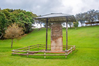 Kolombiya, San Agustin arkeoloji parkında korunaklı bir sığınakla çevrili taş bir heykel..