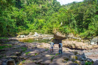 San Agustin, Huila 'daki Magdalena Nehri' nin kayalık kıyılarında yürüyen iki kişi yemyeşil bitki örtüsüyle çevrili..