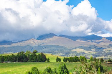 Purac Ulusal Parkı, Cauca, Kolombiya 'da bulutlu bir gökyüzü altındaki yuvarlak tepelerin ve dağların nefes kesici manzarası benzersiz manzaralar ve yemyeşil alanlar sergiliyor..