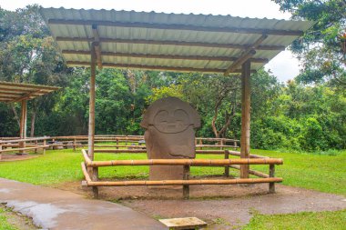 Kolombiya, San Agustin arkeoloji parkındaki bir barınağın altındaki büyük taş bir heykel. Etrafı yemyeşil, Kolombiya öncesi sanat eserleriyle çevrili..