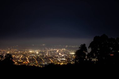 Popayan, Cauca, Kolombiya 'nın çarpıcı gece manzarası, doğayla çevrili karanlık gökyüzüne karşı canlı şehir ışıkları sergiliyor..