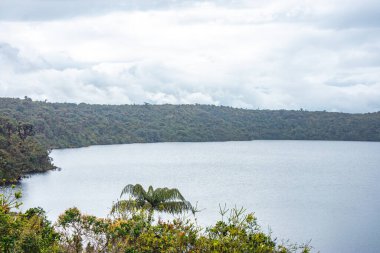 Purace, Cauca, Kolombiya 'da bulutlu bir gökyüzünün altında yemyeşil yemyeşil Öküz Gölü' nü barındıran sakin bir manzara..