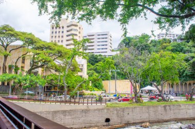 A scenic view of Cat Park in Cali, Valle del Cauca, Colombia, showcasing modern buildings and lush greenery near the river.