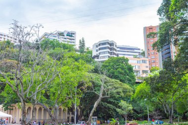 Cali, Kolombiya 'da canlı bir şehir parkı sahnesi, Cali Nehri' nin yanında gür ağaçlar ve modern binalar sergileniyor..