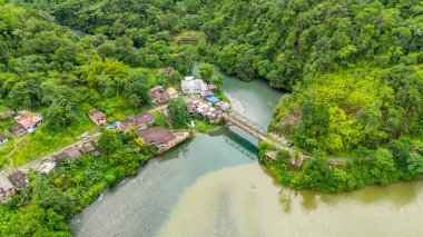Manzara, yemyeşil manzarayı ve kıyıları boyunca küçük evleri olan Agua Clara, Valle del Cauca, Kolombiya nehrini gösteriyor..