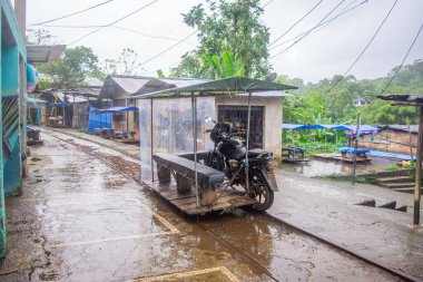 San Cipriano, Buenaventura, Valle del Cauca, Kolombiya 'da yerel kültürü ve yağmurlu havayı gösteren eşsiz bir motosiklet..
