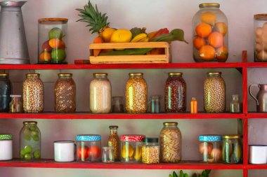 Konserve meyve, sebze ve malzemelerle dolu canlı bir mutfak rafı. Organize ve renkli bir mutfak sergisi sergileniyor..