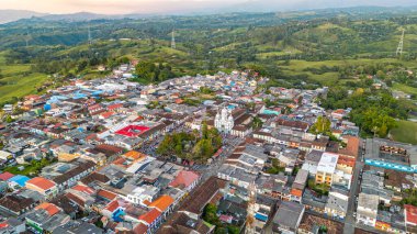 Filandia 'nın canlı çatılarını gösteren, yemyeşil tepeler ve sakin bir akşam gökyüzü tarafından çerçevelenmiş bir hava perspektifi..
