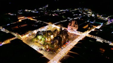 Filandia, Kolombiya 'nın gökyüzü manzarası, geceleri renkli binalar ve ağaçlarla çevrili parlak ışıklı bir meydanı gösteriyor..