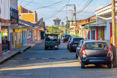 Filandia 'da renkli evler, park edilmiş araçlar ve açık gökyüzünün altında elektrik hatlarının yer aldığı canlı bir sokak sahnesi..