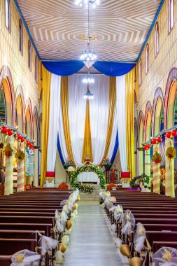 Filandia, Quindio, Kolombiya - 7 Aralık 2025 - Dekoratif kumaşlar ve çiçek düzenlemeleri ile renkli kilise iç mimarisi.