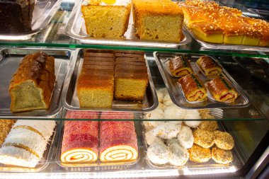 Farklı dokular ve renklerin sergilendiği bir vitrinde çeşitli canlı pasta ve hamur işleri..