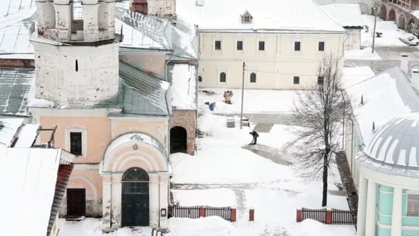 Уборщик чистит снег во дворе монастыря — стоковое видео