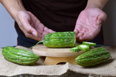 Bir adam ahşap tezgahta yeşil kavun dilimleri gösteriyor..