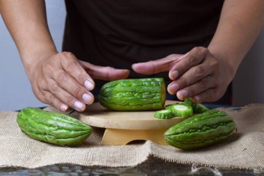 Bir adam ahşap tezgahta yeşil kavun dilimleri gösteriyor..