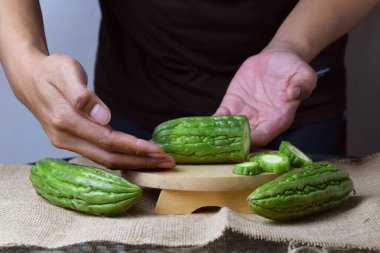 Bir adam ahşap tezgahta yeşil kavun dilimleri gösteriyor..