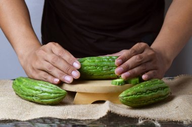 Bir adam ahşap tezgahta yeşil kavun dilimleri gösteriyor..