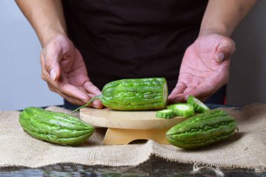 Bir adam ahşap tezgahta yeşil kavun dilimleri gösteriyor..