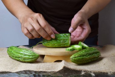 Asyalı bir adamın elini kapatın. Elleri ahşap bir tabanda yeşil kavun ve beyaz bir arka planı olan çuval bezi gösterin..