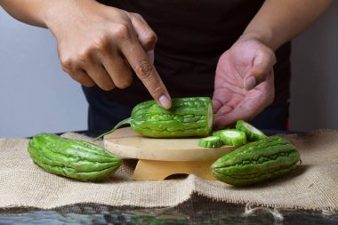 Asyalı bir adamın elini kapatın. Elleri ahşap bir tabanda yeşil kavun ve beyaz bir arka planı olan çuval bezi gösterin..