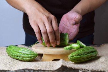 Bir adam ahşap tezgahta yeşil kavun dilimleri gösteriyor..