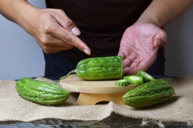 Asyalı bir adamın elini kapatın. Elleri ahşap bir tabanda yeşil kavun ve beyaz bir arka planı olan çuval bezi gösterin..
