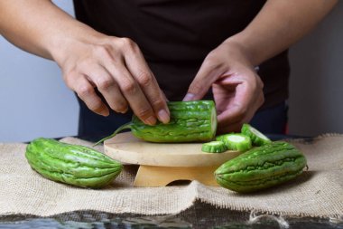 Bir adam ahşap tezgahta yeşil kavun dilimleri gösteriyor..