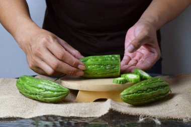 Asyalı bir adamın elini kapatın. Elleri ahşap bir tabanda yeşil kavun ve beyaz bir arka planı olan çuval bezi gösterin..