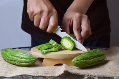 Asyalı bir adam yeşil kavunu kesiyor çuval bezinde ahşap bir taban ve izole beyaz bir zemin ile