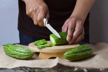 Asyalı bir adam yeşil kavunu kesiyor çuval bezinde ahşap bir taban ve izole beyaz bir zemin ile