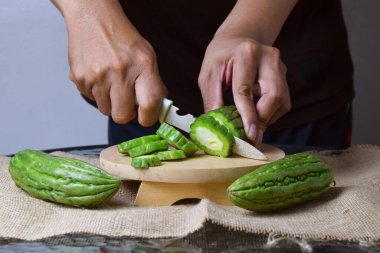 Asyalı bir adam yeşil kavunu kesiyor çuval bezinde ahşap bir taban ve izole beyaz bir zemin ile