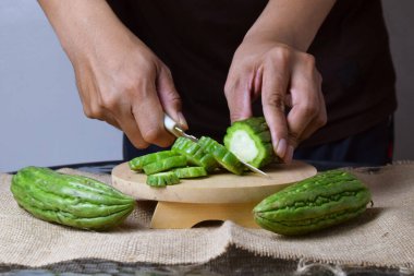 Asyalı bir adam yeşil kavunu kesiyor çuval bezinde ahşap bir taban ve izole beyaz bir zemin ile