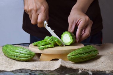 Asyalı bir adam yeşil kavunu kesiyor çuval bezinde ahşap bir taban ve izole beyaz bir zemin ile