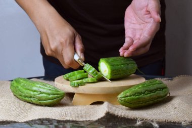 Asyalı bir adam yeşil kavunu kesiyor çuval bezinde ahşap bir taban ve izole beyaz bir zemin ile