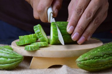 Çuval bezi ve izole edilmiş beyaz arkaplan üzerine ahşap tabanlı yeşil kavun kesen Asyalı bir adamın elini yakın plan çek..