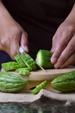Çuval bezi ve izole edilmiş beyaz arkaplan üzerine ahşap tabanlı yeşil kavun kesen Asyalı bir adamın elini yakın plan çek..