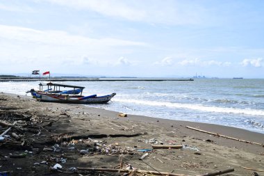Cilacap, Endonezya - 18 Haziran 2025: Cilacap, Orta Java 'da yerel tekne ve turistlerin bulunduğu kumlu sahil manzarası.