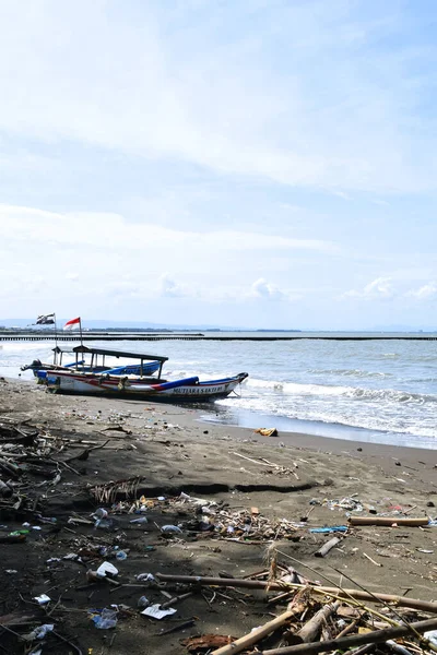 Cilacap, Endonezya - 18 Haziran 2025: Cilacap, Orta Java 'da yerel tekne ve turistlerin bulunduğu kumlu sahil manzarası.