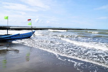 Cilacap, Endonezya - 18 Haziran 2025: Yerel bir tekne Cilacap, Central Java bölgesindeki kumlu bir plaja inerken mavi denizde hizaya sokuldu.