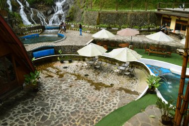 Purwokerto, Endonezya - 20 Haziran 2025: Geleneksel taş ve ahşap süslemeleri olan bir şelale yakınında bir doğa temalı restoran Purwokerto, Endonezya 'da yer almaktadır..