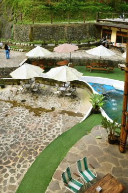 Purwokerto, Endonezya - 20 Haziran 2025: Geleneksel taş ve ahşap süslemeleri olan bir şelale yakınında bir doğa temalı restoran Purwokerto, Endonezya 'da yer almaktadır..