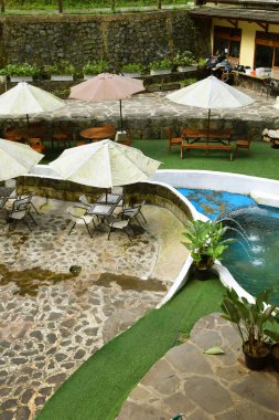 Purwokerto, Endonezya - 20 Haziran 2025: Geleneksel taş ve ahşap süslemeleri olan bir şelale yakınında bir doğa temalı restoran Purwokerto, Endonezya 'da yer almaktadır..