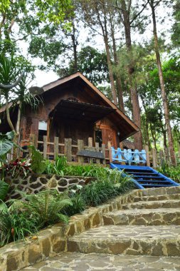 Endonezya, Batı Java, Kuningan 'da yemyeşil tropik bahçelerle çevrili mavi merdivenleri ve çitleri olan büyüleyici bir ahşap kulübe..