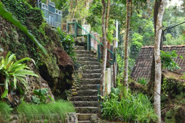 Endonezya, Batı Java, Kuningan 'daki bir bahçedeki yemyeşil bir yamaca açılan renkli pencerelerle dekore edilmiş eşsiz bir taş merdiven..